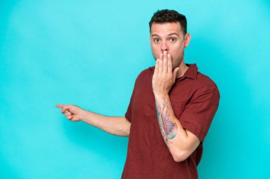 Mavi arka planda mahsur kalmış beyaz, yakışıklı genç bir adam. Sürpriz bir ifadeyle.