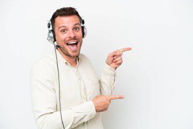 Tele pazarlamacı, beyaz arka planda izole edilmiş bir kulaklıkla çalışan beyaz bir adam şaşırmış ve işaret ediyor.