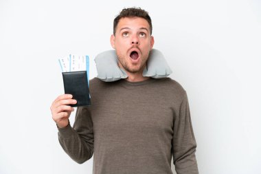 Beyaz arka planda izole edilmiş pasaport taşıyan genç beyaz bir adam yukarı bakıyor ve şaşırmış bir ifadeyle