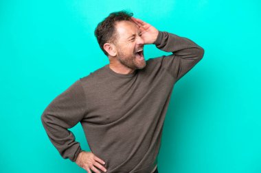 Orta yaşlı beyaz bir adam mavi arka planda izole edilmiş, çok gülümsüyor.