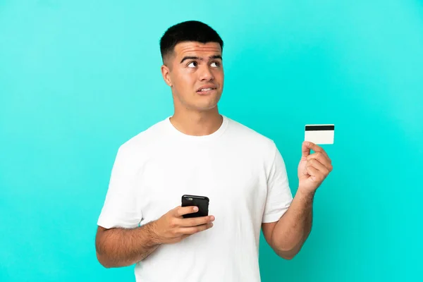 Mladý Pohledný Muž Přes Izolované Modré Pozadí Nákup Mobilem Kreditní — Stock fotografie