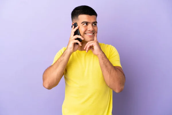 Молодий Красивий Чоловік Використовує Мобільний Телефон Над Ізольованим Фіолетовим Фоном — стокове фото