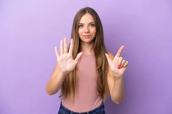 若いリトアニア人女性は紫色の背景に7本指で数える — ストック写真