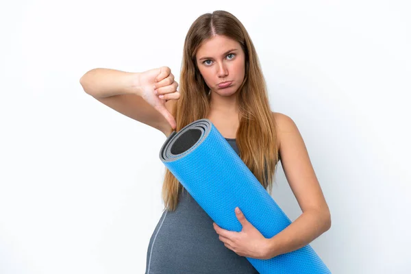 年轻的女运动员一边去上瑜伽课 一边拿着垫子 带着负面的表情展示着大拇指 — 图库照片