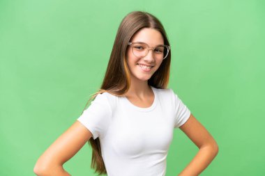 Kafkas kökenli genç bir kız kolları kalçasında poz veriyor ve gülümsüyor.