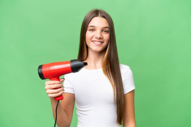Kafkasyalı genç bir kız izole edilmiş arka planda saç kurutma makinesini tutarken gülümsüyor.