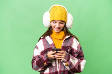Kafkasyalı genç bir kız izole edilmiş arka planda kışlık kuklalar takıyor ve cep telefonuyla bir mesaj gönderiyor.