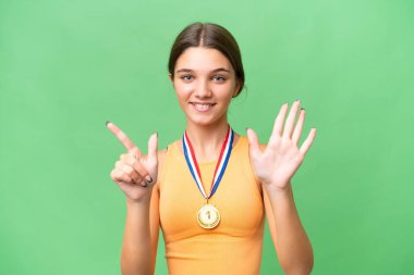 İzole edilmiş arka planda madalyaları olan beyaz kız yediyi parmaklarıyla sayıyor.