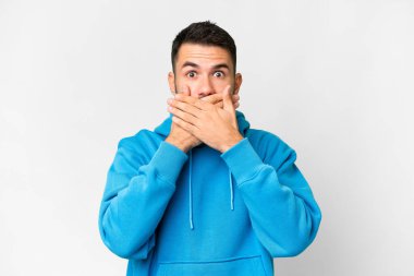 İzole edilmiş beyaz arka planı olan yakışıklı beyaz bir adam elleriyle ağzını kapatıyor.