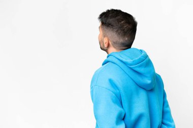 Genç, yakışıklı beyaz bir adam izole edilmiş beyaz arka planda ve geriye bakıyor.