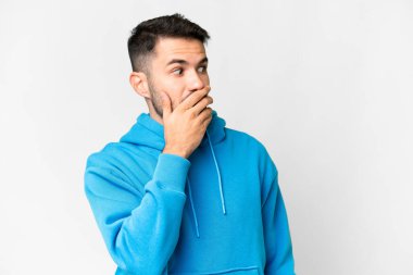 Beyaz arka plan üzerinde genç, yakışıklı beyaz bir adam. Yan tarafa bakarken sürpriz jest yapıyor.