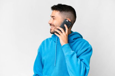 İzole edilmiş beyaz bir geçmişi olan yakışıklı beyaz bir adam cep telefonuyla sohbet ediyor.