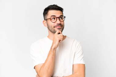 İzole edilmiş beyaz arka planı olan yakışıklı beyaz bir adam yukarı bakarken bir fikir düşünüyor.