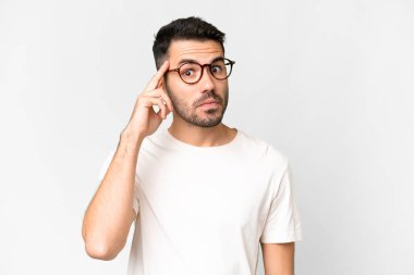 Soyutlanmış beyaz bir arka planda yaşayan yakışıklı beyaz bir adam bir fikir düşünüyor.