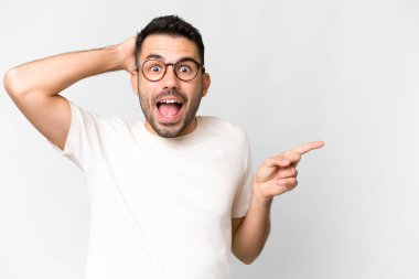 Young handsome caucasian man over isolated white background surprised and pointing finger to the side