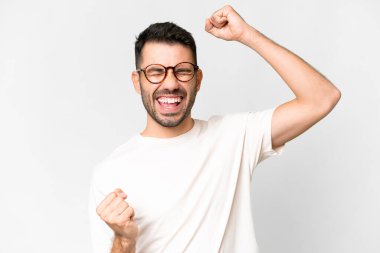 Soyutlanmış beyaz arka planda genç, yakışıklı beyaz adam zaferi kutluyor.