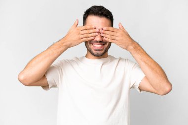 İzole edilmiş beyaz arka planda genç, yakışıklı, beyaz bir adam. Gözleri kapalı ve gülümsüyor.