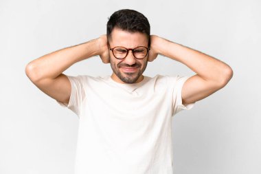 İzole edilmiş beyaz arka planı olan yakışıklı beyaz adam hayal kırıklığına uğramış ve kulaklarını kapatmış.