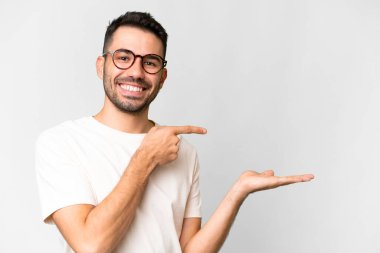 İzole edilmiş beyaz arka plan üzerinde yakışıklı beyaz bir adam bir ilan vermek için fotokopi makinesini avucunun içinde tutuyor.