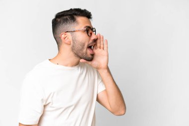 Beyaz arka planda yaşayan yakışıklı beyaz bir adam ağzı sonuna kadar açık bağırıyor.