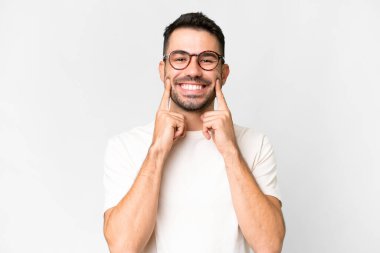 İzole edilmiş beyaz bir arka planı olan yakışıklı beyaz bir adam mutlu ve hoş bir ifadeyle gülümsüyor.