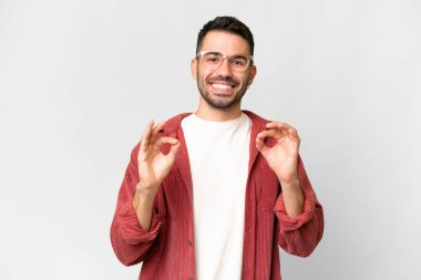 Young handsome caucasian man over isolated white background showing ok sign with two hands