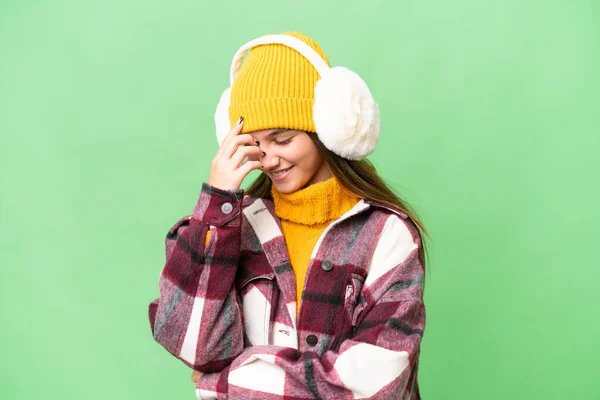 stock image Teenager caucasian girl wearing winter muffs over isolated background laughing