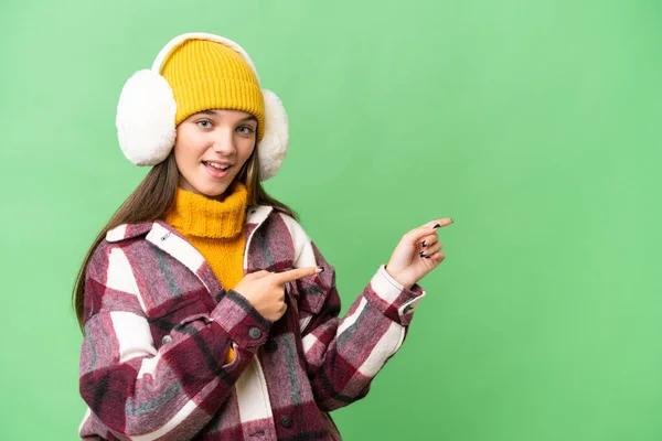 Teenager Caucasian Girl Wearing Winter Muffs Isolated Background Surprised Pointing — 스톡 사진