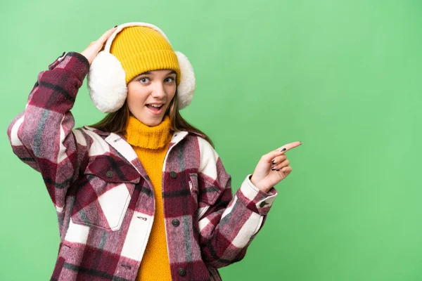 Teenager Caucasian Girl Wearing Winter Muffs Isolated Background Surprised Pointing — Stock Photo, Image