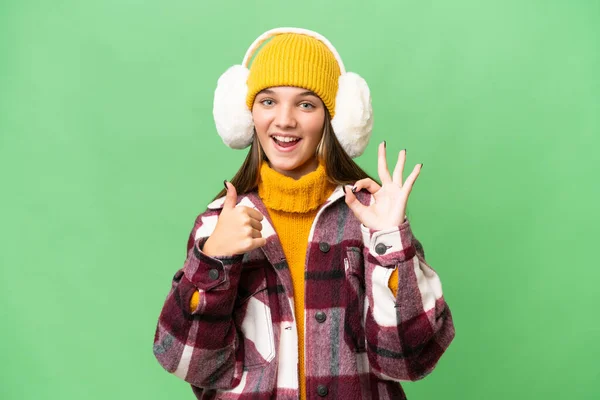 年轻的高加索女孩披着冬衣 站在与世隔绝的背景上 露出好的手势和竖起大拇指的姿势 — 图库照片