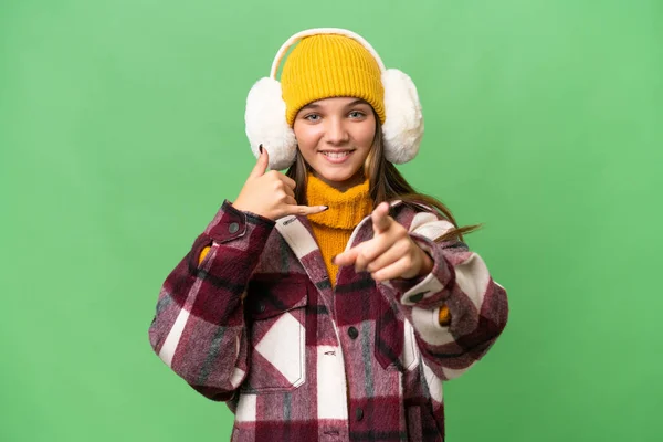 十几岁的高加索女孩穿着冬衣 在孤立的背景下做着电话手势 指着前方 — 图库照片