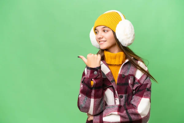 年轻的高加索女孩穿着冬衣 背景孤立 指向侧面 展示了一种产品 — 图库照片