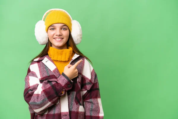年轻的高加索女孩穿着冬衣 背景孤立 指向侧面 展示了一种产品 — 图库照片