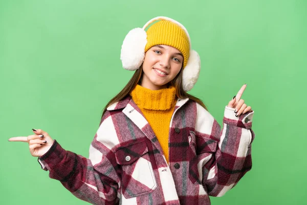 年少无知的高加索女孩披着冬衣 带着孤立的背景 手指指向侧边 快乐极了 — 图库照片