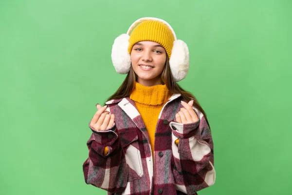 年轻的高加索女孩穿着冬衣 背景偏僻 做着赚钱的姿势 — 图库照片