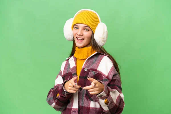 年轻的高加索女孩披着冬衣 背景孤寂 指向前方 面带微笑 — 图库照片