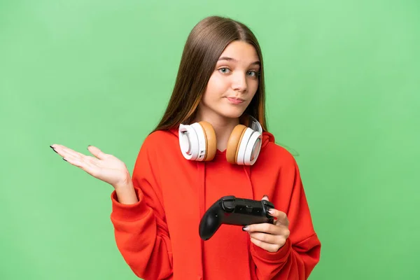 十几岁的女孩在一个与世隔绝的背景下与电子游戏控制器玩耍 一边举手一边表示怀疑 — 图库照片