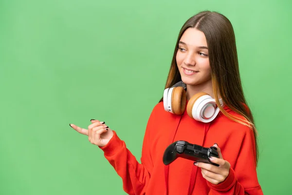 十几岁的白人女孩在一个孤立的背景下玩电子游戏控制器 手指指向侧边 — 图库照片