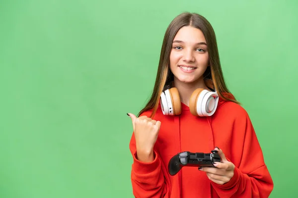 十几岁的女孩在一个孤立的背景下和一个电子游戏控制器一起玩 指向侧面来展示一个产品 — 图库照片