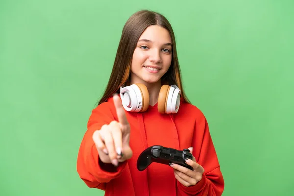 青少年白种人女孩在一个孤立的背景下玩电子游戏控制器 显示并举起一个手指 — 图库照片