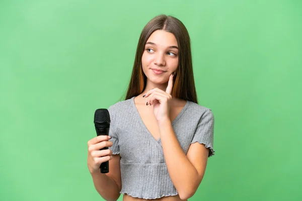 Teenager Singer Girl Picking Microphone Isolated Background Thinking Idea While — Foto de Stock