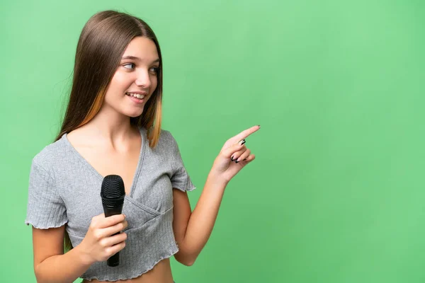 Adolescente Cantante Chica Recogiendo Micrófono Sobre Fondo Aislado Señalando Dedo — Foto de Stock