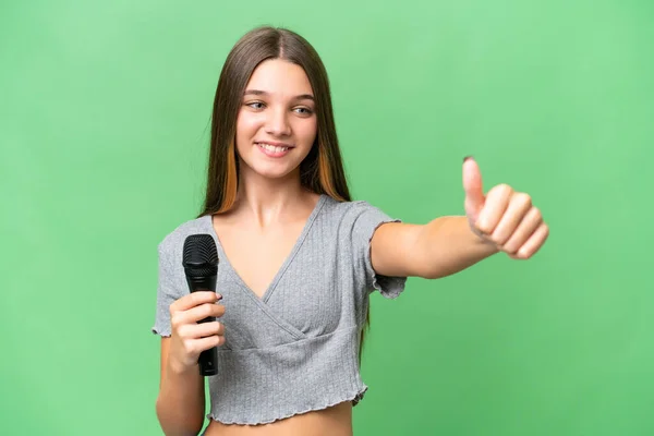 Adolescente Cantante Chica Recogiendo Micrófono Sobre Aislado Fondo Dando Pulgar — Foto de Stock