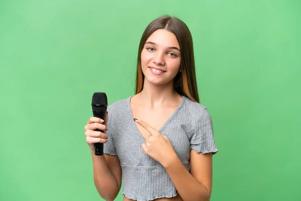 Adolescente Cantante Chica Recogiendo Micrófono Sobre Aislado Fondo Apuntando Lado — Foto de Stock