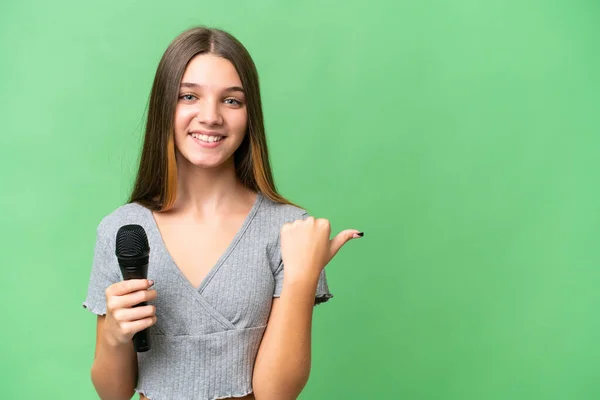 Adolescente Cantante Chica Recogiendo Micrófono Sobre Aislado Fondo Apuntando Lado — Foto de Stock