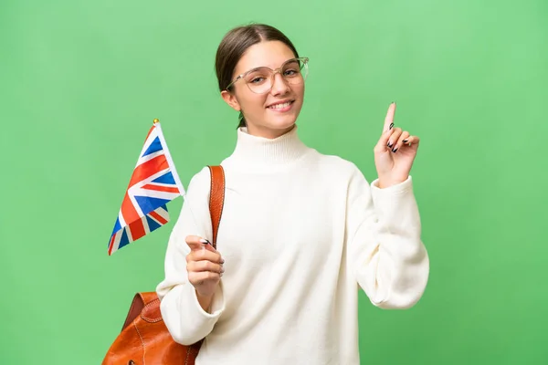 十几岁的学生高傲地拿着英国国旗 站在孤立的背景上 举手表决 表示自己是最好的学生 — 图库照片