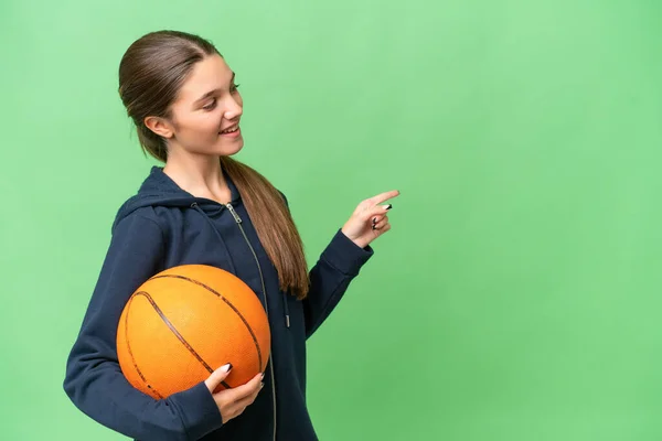 十几岁的女孩在一个孤立的背景下打篮球 手指指向旁边 并展示了一种产品 — 图库照片