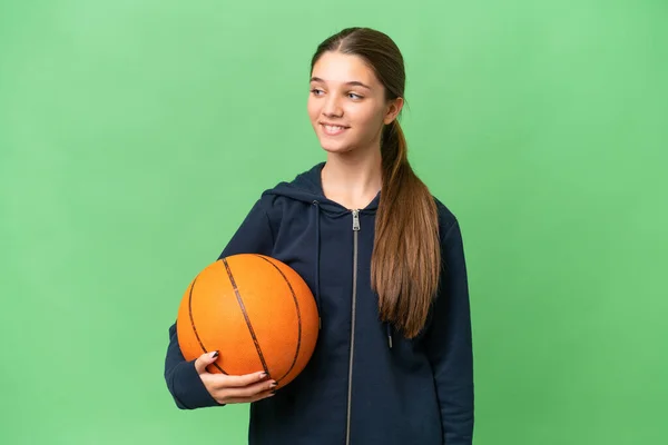 ティーンCaucasian女の子プレイバスケットボール上の隔離された背景見ますへザ側と笑顔 — ストック写真