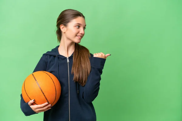 十几岁的白人女孩在一个与世隔绝的背景下打篮球 指着旁边介绍自己的产品 — 图库照片