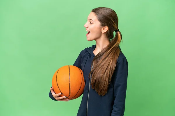 青少年白种人女孩打篮球而不顾孤立的背景 侧身大笑着 — 图库照片